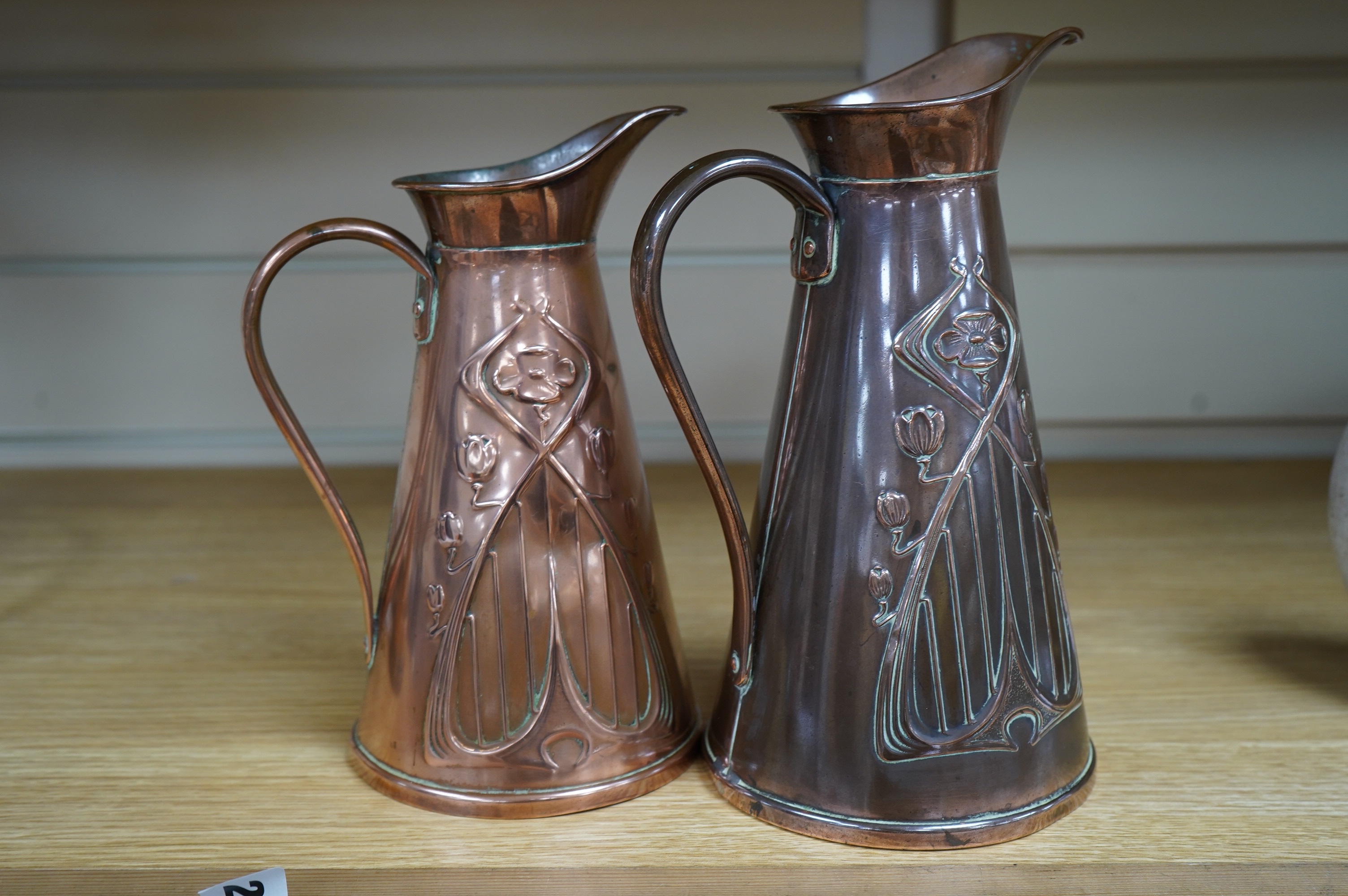 Two Joseph Sankey Art Nouveau embossed copper jugs, tallest 23cm. Condition- fair to good